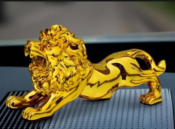 "Golden lion figurine placed on a car dashboard, symbolizing power and luxury." "Small decorative golden lion ornament on a vehicle dashboard." "Elegant golden lion statue used as a car interior decoration piece." "Metallic golden lion figurine enhancing the car’s dashboard aesthetics."